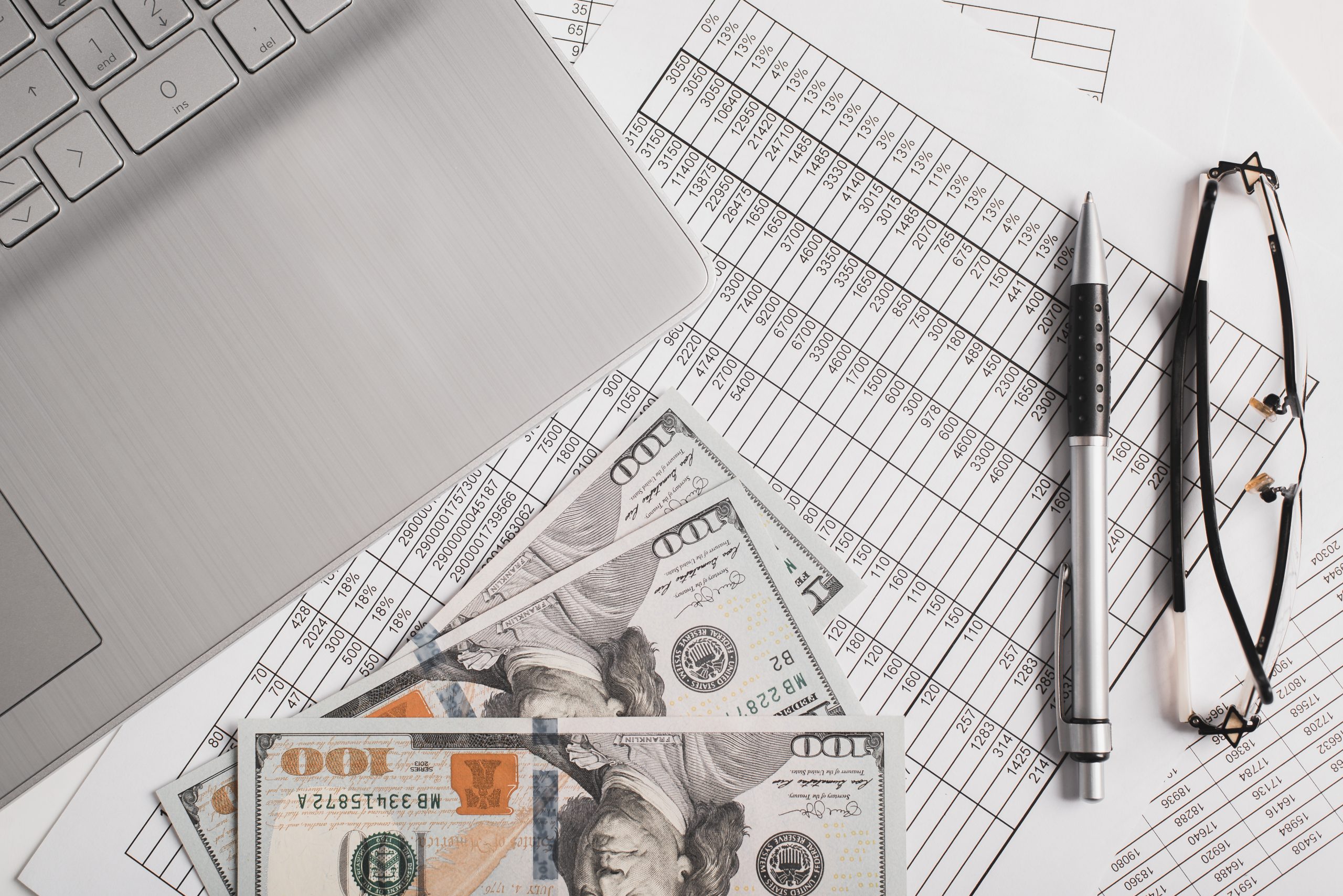 Taxes, business and finance concept. Top view money, invoice documents, laptop, pen and eyeglasses at workplace
